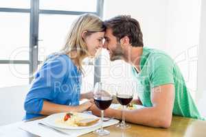 Young couple sitting face to face at dinning table