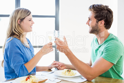 Young couple toasting wine glasses while having meal Young couple toasting wine glasses while having meal