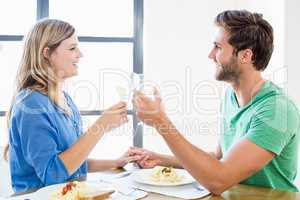 Young couple toasting wine glasses while having meal