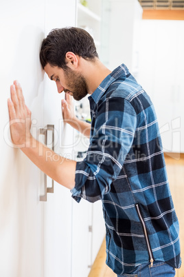 Depressed man leaning his head against a door