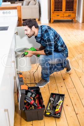 Man drilling a hole inside the cabinet