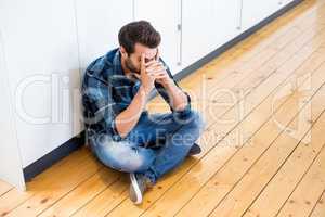 Tensed man sitting on wooden floor