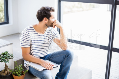 Man sitting with laptop looking out through window