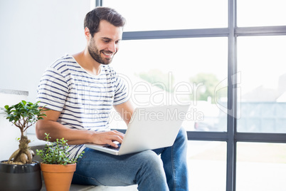 Happy man sitting on steps using laptop