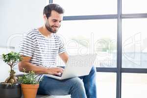 Happy man sitting on steps using laptop