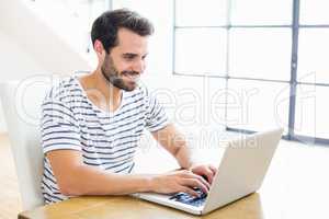 Happy man sitting on table and using laptop