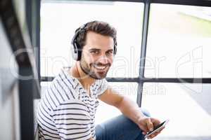 Portrait of man on steps listening to music on mobile phone