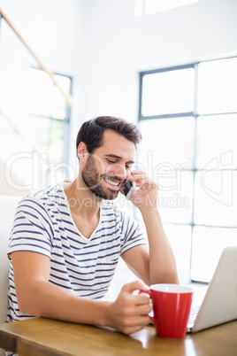 Man having coffee while talking on phone Man having coffee while talking on phone
