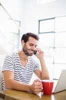 Man having coffee while talking on phone