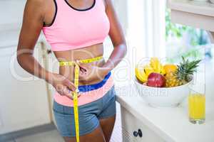 Mid-section of woman measuring her waist