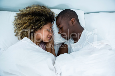 Young couple sleeping face to face on bed
