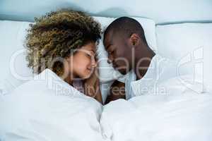 Young couple sleeping face to face on bed