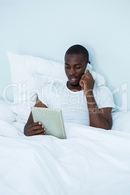 Man looking at digital tablet while talking on phone