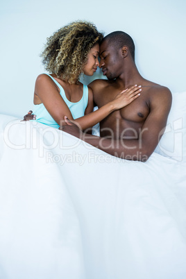 Young couple embracing face to face on bed