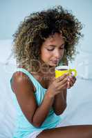 Young woman drinking a coffee on bed