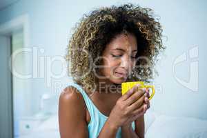 Young woman drinking a coffee on bed