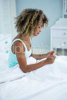 Young woman in bed looking at medicine