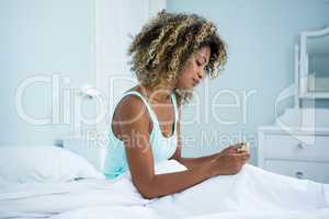 Young woman in bed looking at medicine