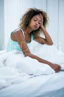 Tensed woman sitting on bed in bedroom