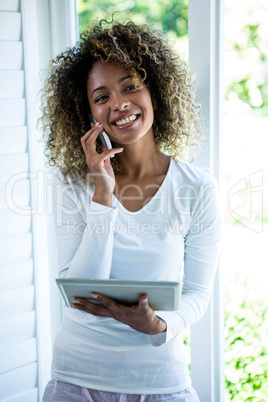 Woman talking on the phone while using the digital tablet