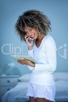 Woman talking on the phone while using the digital tablet