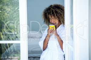 Young woman holding a cup of coffee and looking out of the windo