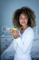 Young woman holding a cup of coffee and looking away