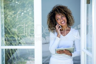 Woman talking on the phone while using the digital tablet