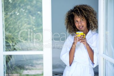 Young woman holding a cup of coffee and looking out of the windo