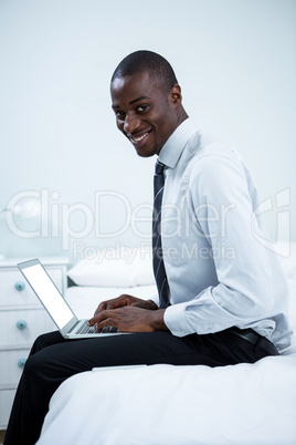 Happy young man using laptop on bed