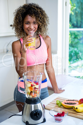 Happy woman drinking juice while listening to music