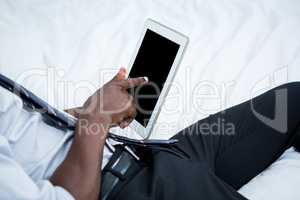 Mid-section of man using digital tablet on bed