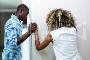 Upset couple standing on opposite sides of the wall