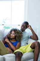 Couple embracing while sitting on sofa in living room