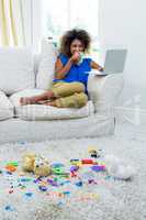 Young woman using laptop while having coffee in living room