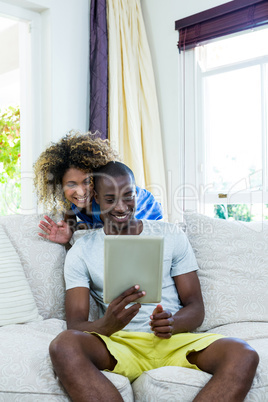 Happy young couple using a digital tablet in living room