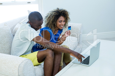 Young couple doing online shopping on laptop in living room