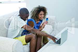 Young couple doing online shopping on laptop in living room
