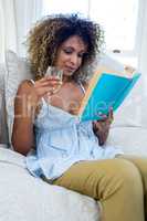 Woman reading book while having wine