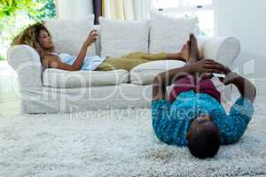 Woman watching television while man lying on rug