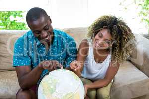 Couple sitting on sofa and looking at a globe