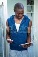 Happy young man using digital tablet and phone on bed