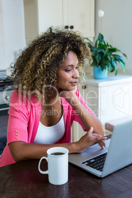 Young woman using laptop with coffee on table