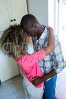 Young couple embracing face to face in kitchen