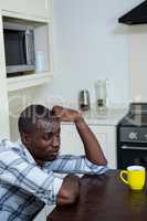 Thoughtful man leaning on table with a cup of coffee