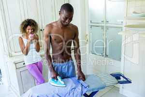 Young man ironing a shirt in kitchen
