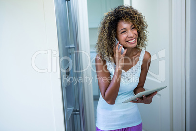 Woman talking on the phone while using the digital tablet