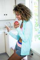 Young woman text messaging on phone in kitchen