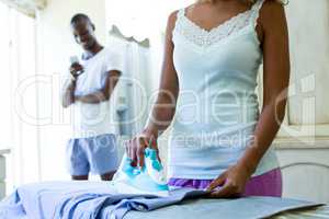 Mid-section of woman ironing a shirt in kitchen