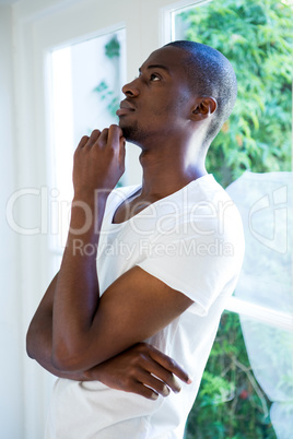 Thoughtful young man standing near the window